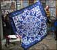 Colorful applique bedspread sewn by the man displaying it